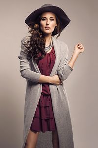 Fashionable woman in a hat, dress and long grey sweater, accessories, high heels, posing in studio. Fashion autumn photo